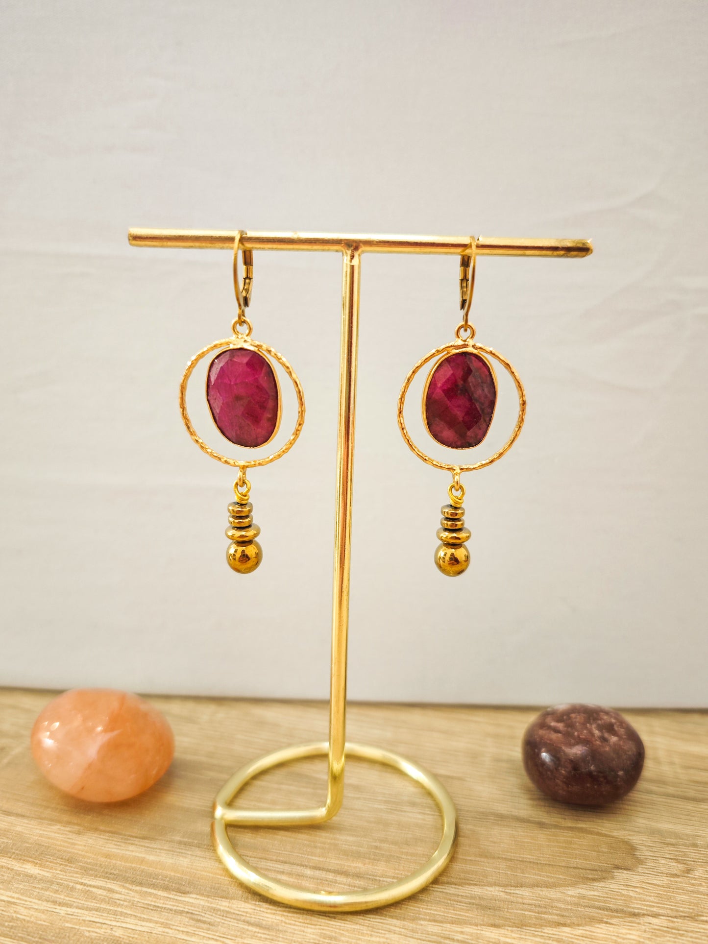 Boucles d’oreilles artisanales rouges en rubis facetté sur acier inoxydable doré présentées sur un support doré.