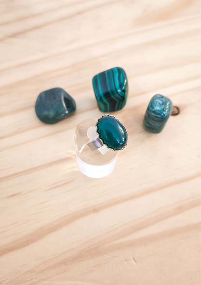 Bague artisanale en agate verte montée sur une base ajustable en acier inoxydable, posée sur fond neutre, création faite main et pièce unique.