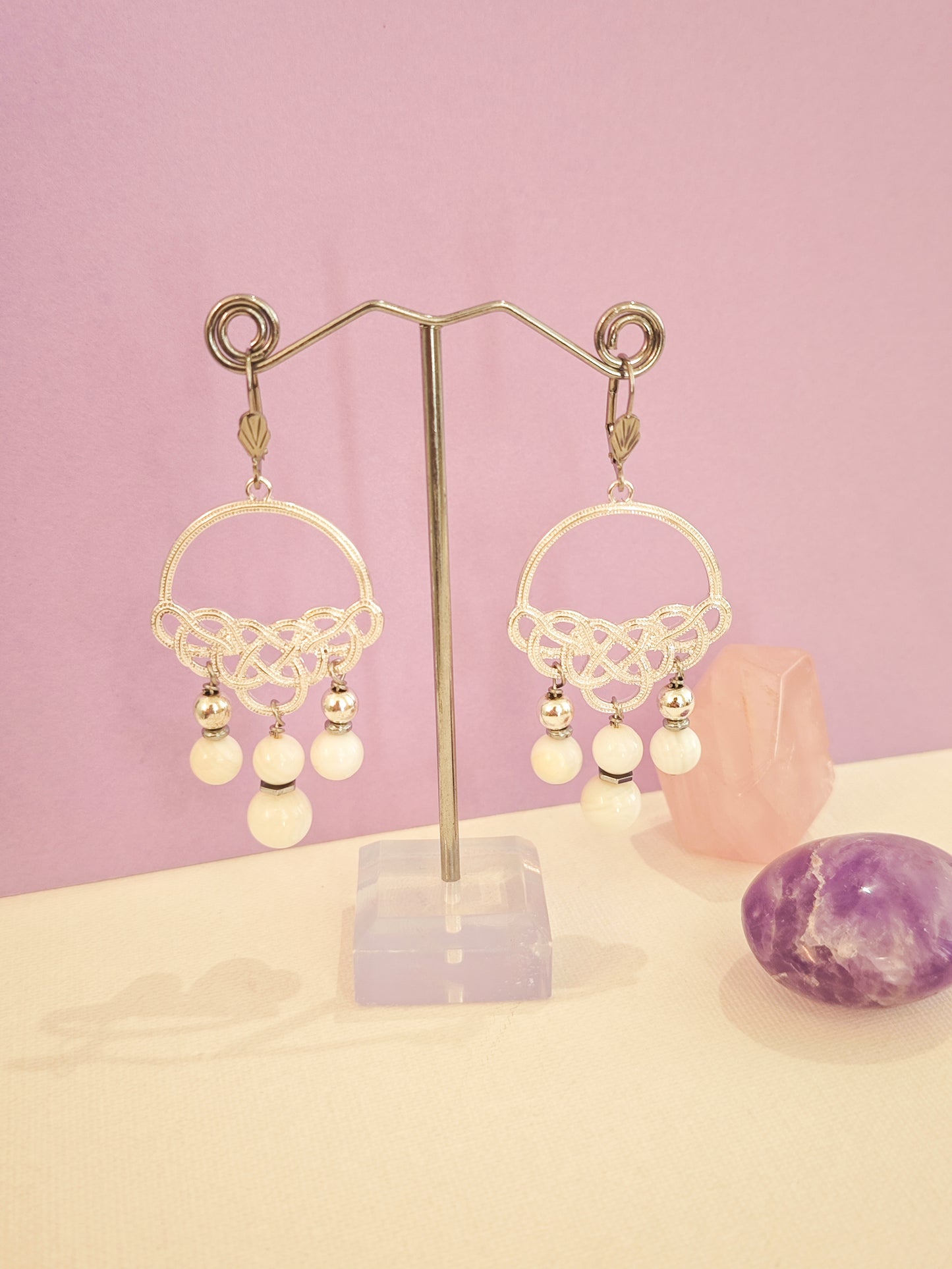 Boucles d’oreilles artisanales en acier inoxydable avec nacre blanche, création unique Julie Gassmann sur fond rose et beige.