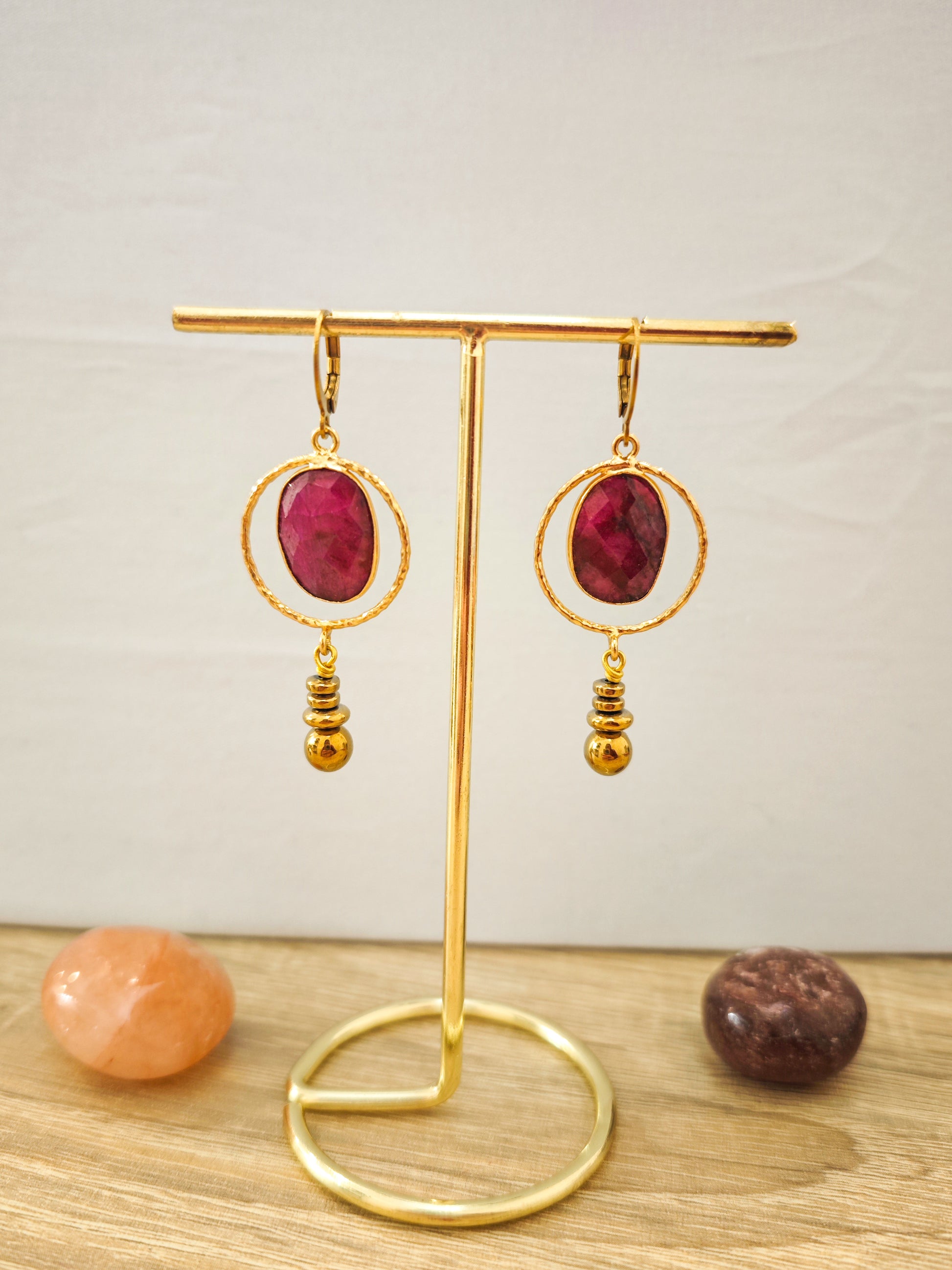 Boucles d’oreilles artisanales rouges en rubis facetté sur acier inoxydable doré présentées sur un support doré.