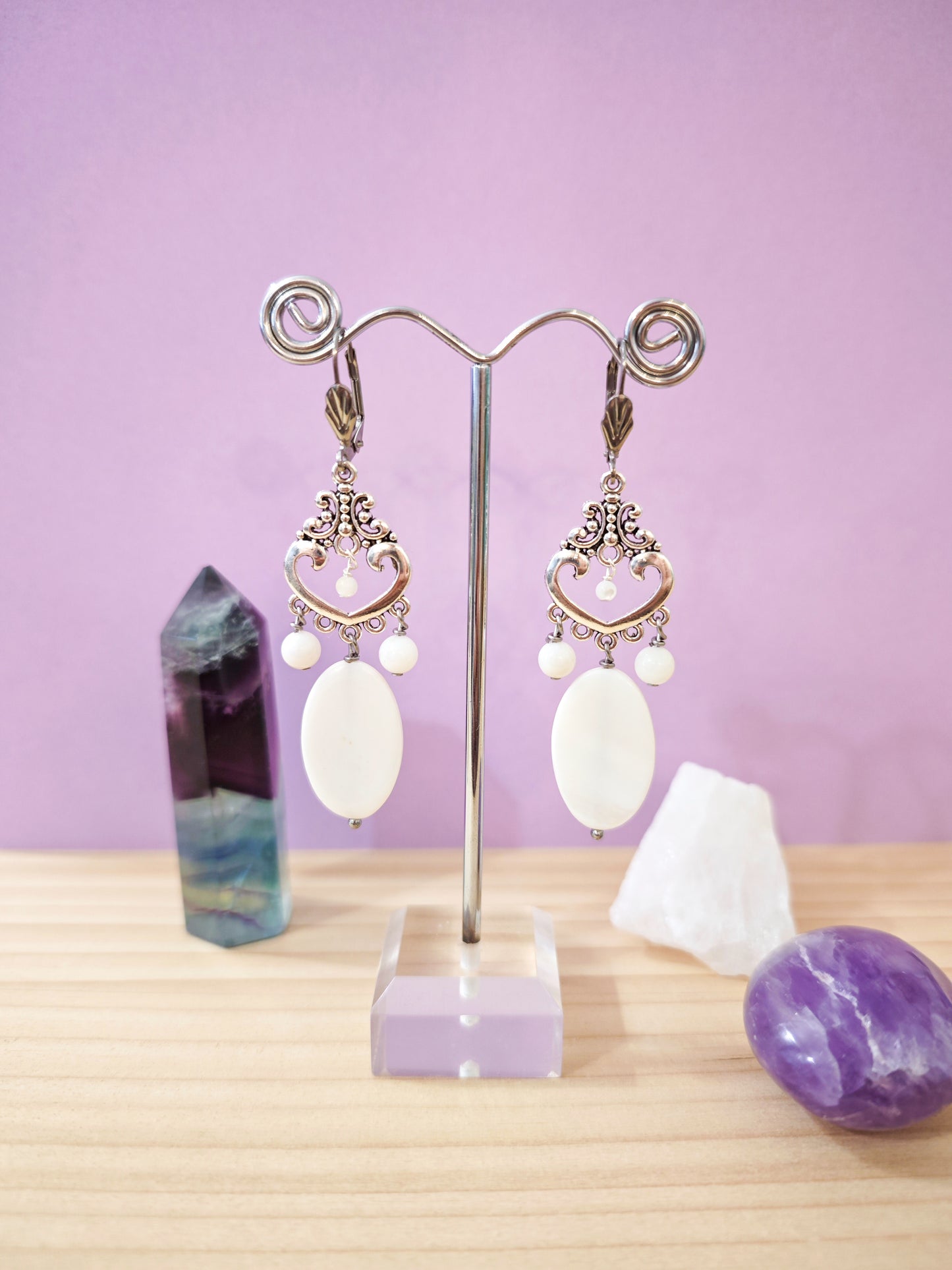 Boucles d’oreilles pendantes en nacre blanche avec motif cœur ajouré et dormeuses en acier inoxydable, création artisanale Julie Gassmann.