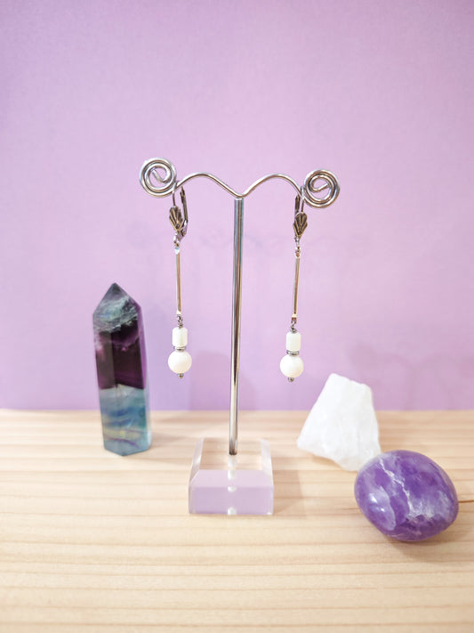 Boucles d’oreilles minimalistes en nacre blanche avec perles suspendues sur dormeuses en acier inoxydable, création artisanale Julie Gassmann.