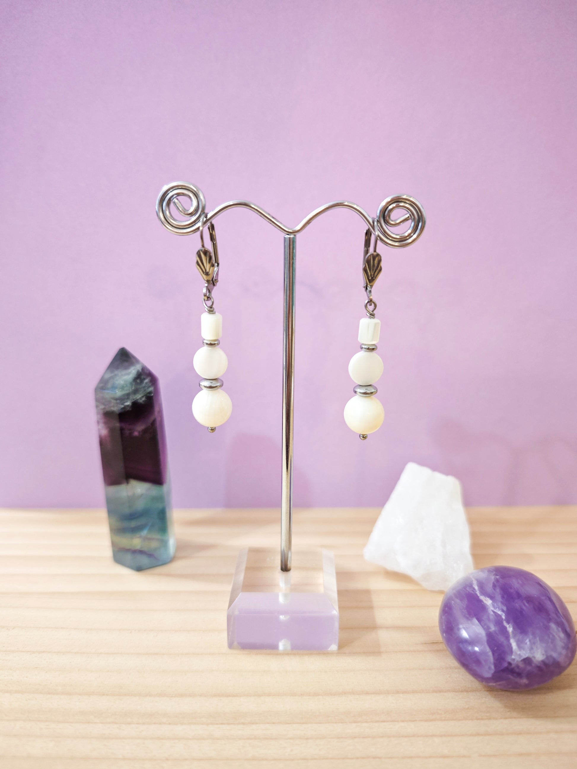 Boucles d’oreilles pendantes avec perles de nacre blanche montées sur dormeuses en acier inoxydable, création artisanale Julie Gassmann.