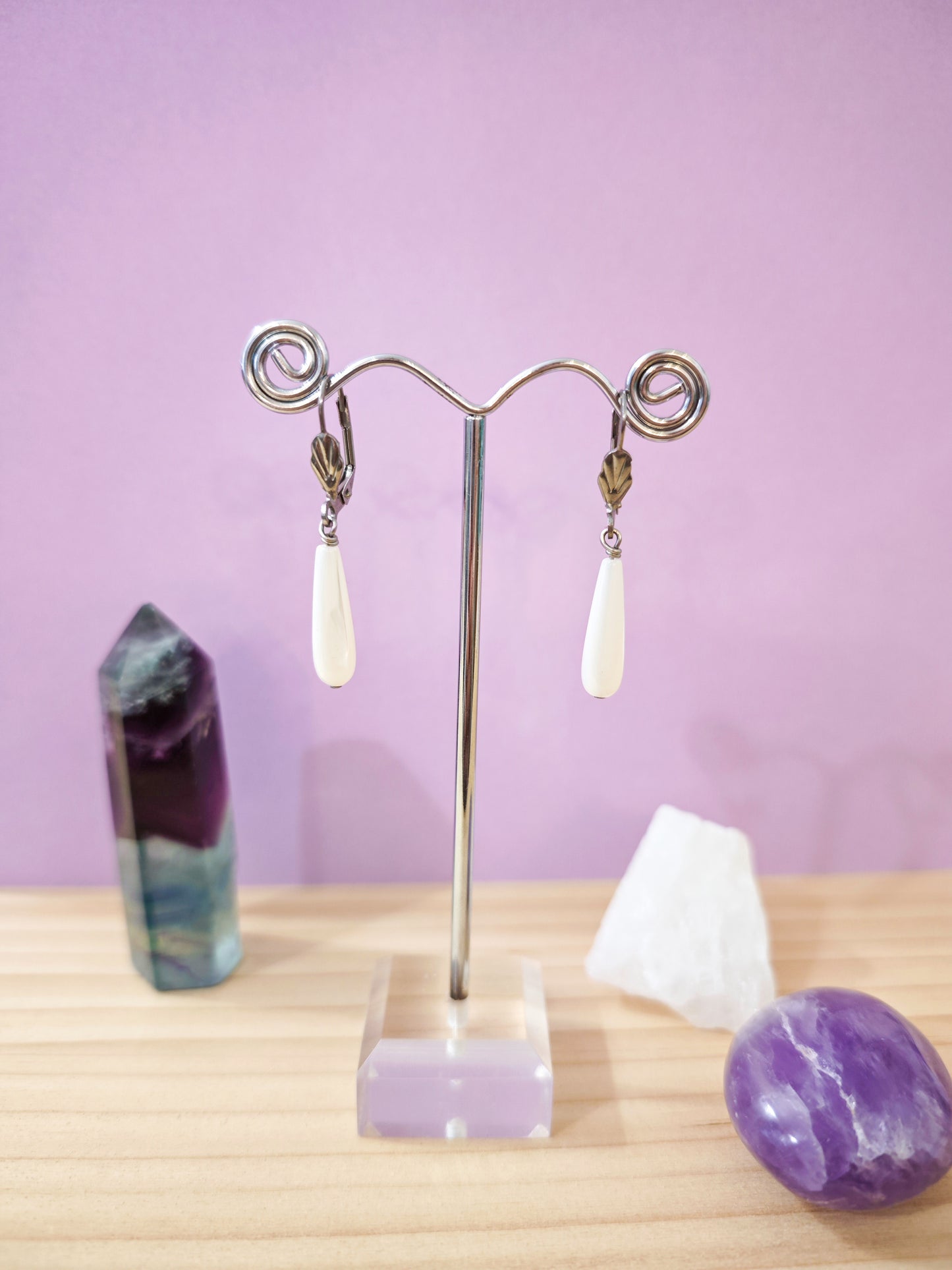 Boucles d’oreilles pendantes en nacre blanche en forme de goutte montées sur dormeuses en acier inoxydable, création artisanale Julie Gassmann.