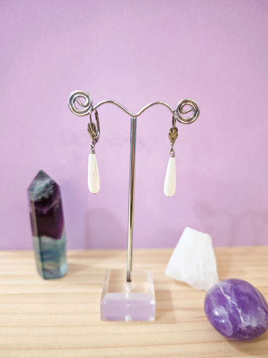 Boucles d’oreilles pendantes en nacre blanche en forme de goutte montées sur dormeuses en acier inoxydable, création artisanale Julie Gassmann.
