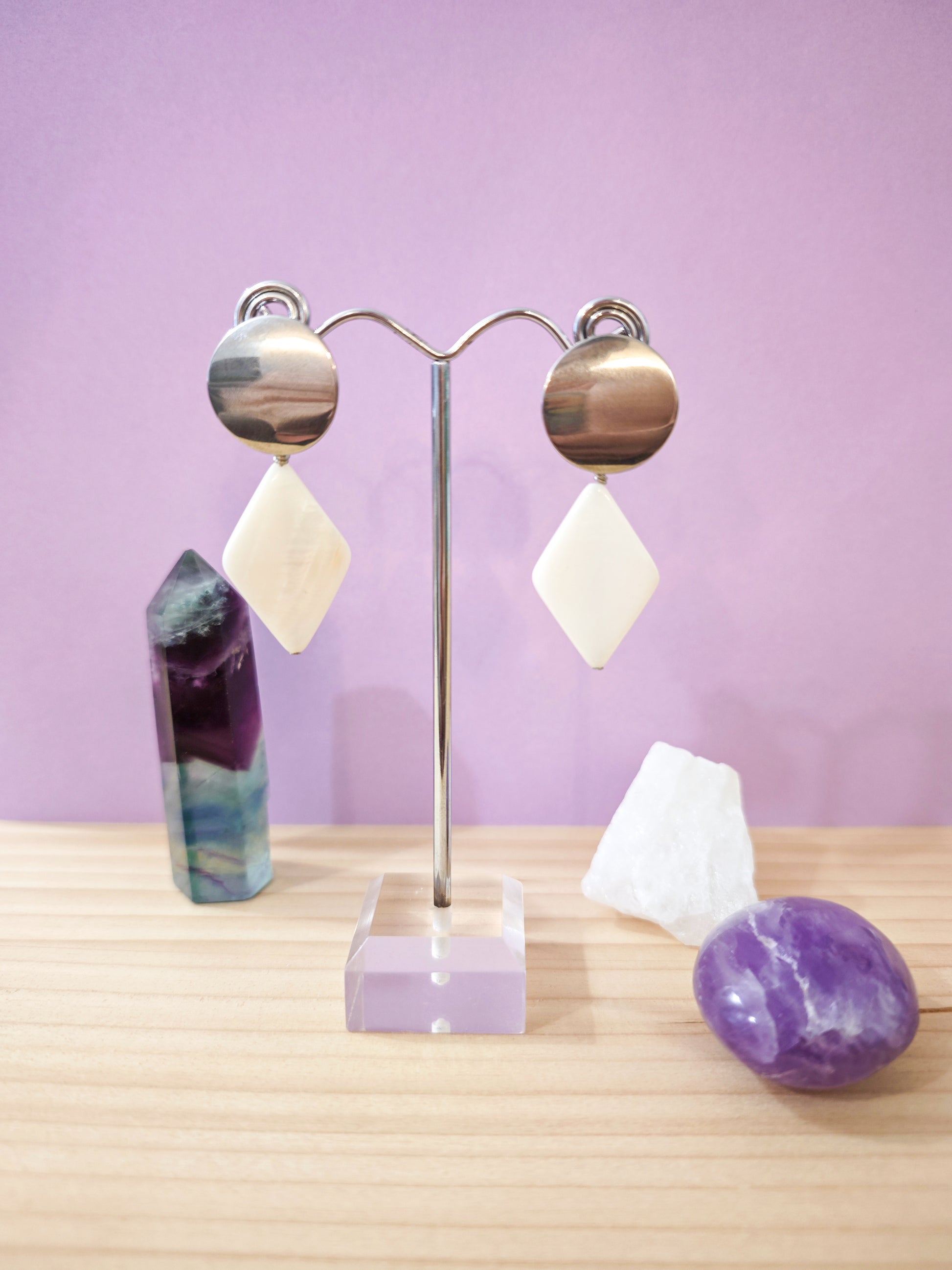 Boucles d’oreilles pendantes avec nacre blanche en forme de losange montées sur dormeuses en acier inoxydable, création artisanale Julie Gassmann.